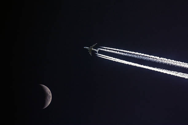 Plane with moon Plane in night with contrails and moon contrail moon on a night sky stock pictures, royalty-free photos & images