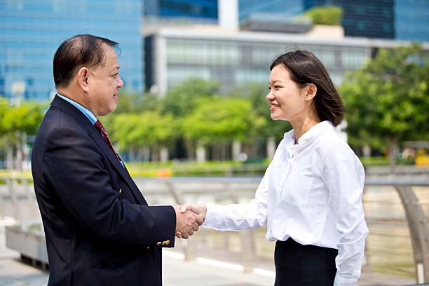 istock Asian businessman and young female shake hands 475012408