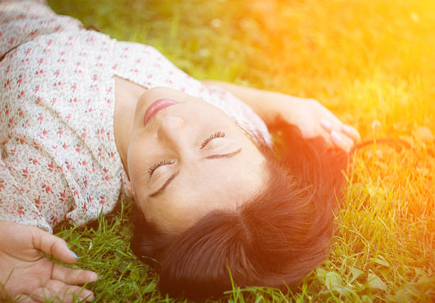 Cute young woman lying on the grass. Soft focus with shallow depth of field. 