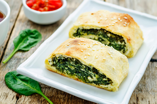 strudel with spinach and ricotta on a dark wood background. the toning. selective focus