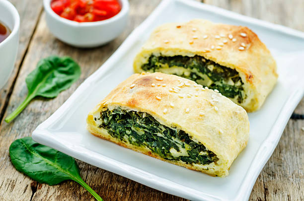 strudel with spinach and ricotta strudel with spinach and ricotta on a dark wood background. the toning. selective focus strudel stock pictures, royalty-free photos & images