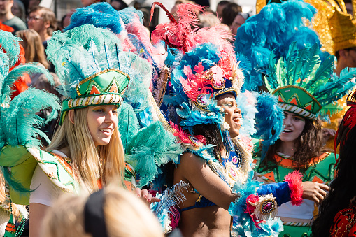 Berlin, Germany - May 24, 2015: three young interracial girls in colorful carnival costumes among a cheering crowd of people in the berlin carnival of cultures