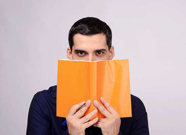 istock Teacher holding a book with blank orange cover. 475034337