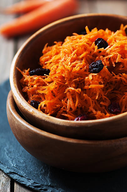 Carrot salad with raisins on the wooden table,