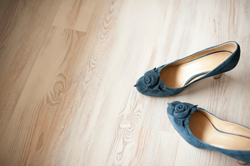 Detail of blue suede leather women shoes isolated on white wooden floor. A lot of copy space. Horizontal color image. 