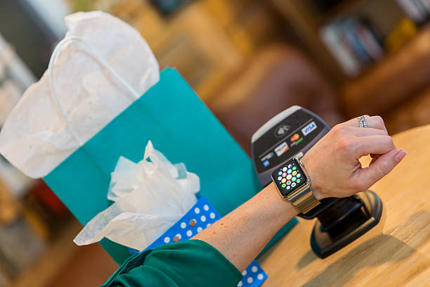 femme payer à l'aide d'apple watch et panneau de messages informatisé  - american express photos photos et images de collection