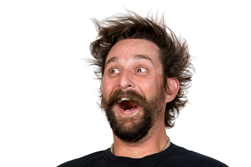 Goofy young man, with full beard and moustache and wild hair style, screams with joy. Studio portrait over white. Space for your text.