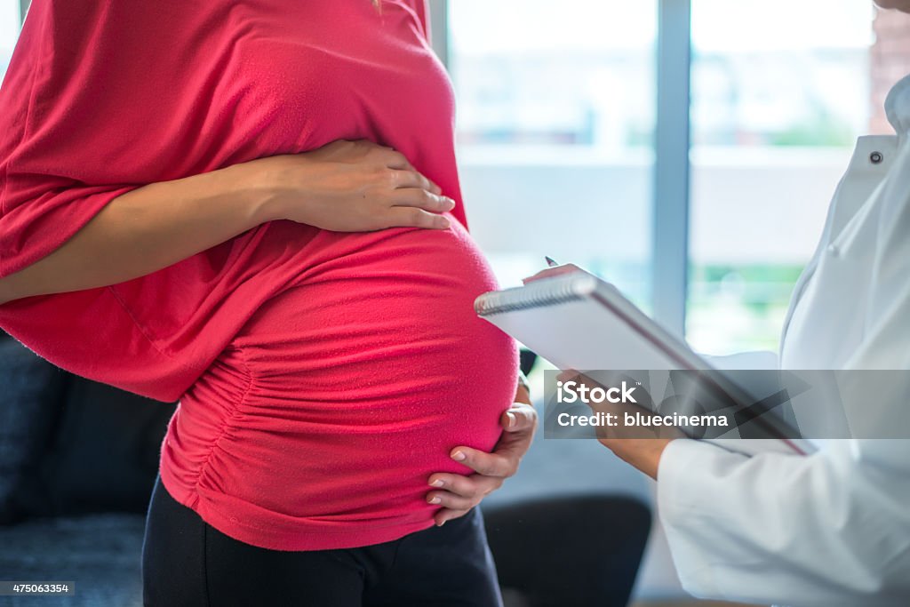 Mujer embarazada con médico - Foto de stock de 2015 libre de derechos