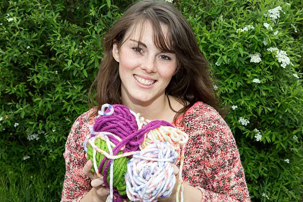young woman smiles and holds bale of wool