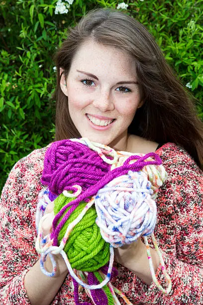 young woman smiles and holds bale of wool