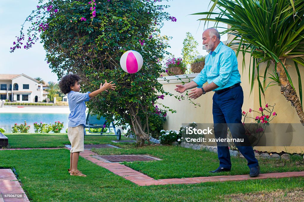 Playing with his grandson Middle Eastern grandfather with his grandson playing with a ball in the garden. Dubai Stock Photo