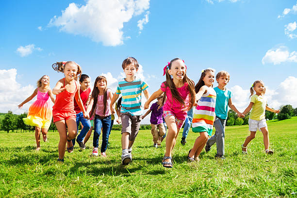 Group of kids running over grass on a sunny day stock photo