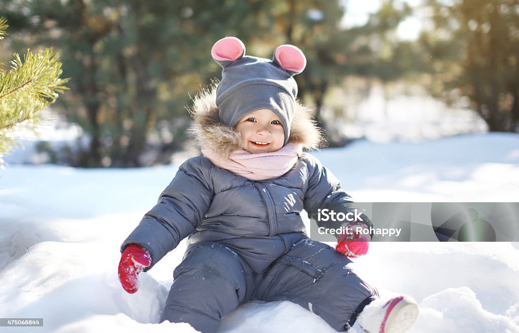 Funny child playing on the snow in warm sunny winter Funny child playing on the snow in warm sunny winter day 2015 Stock Photo