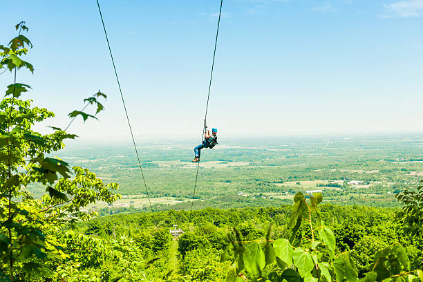 Zip-lining Young woman zip-lining with aerial countryside view at Blue Mountain, Ontario, Canada. zip line stock pictures, royalty-free photos & images