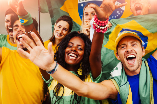 Brazil football supporter on stadium. Brazilian fans on soccer pitch watching team play. Group of supporters with flag and national jersey cheering for Brazil. Championship game.