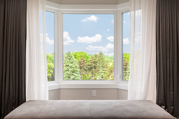 Bay window with summer view Bay window with drapes, curtains and view of trees under summer sky bay window stock pictures, royalty-free photos & images