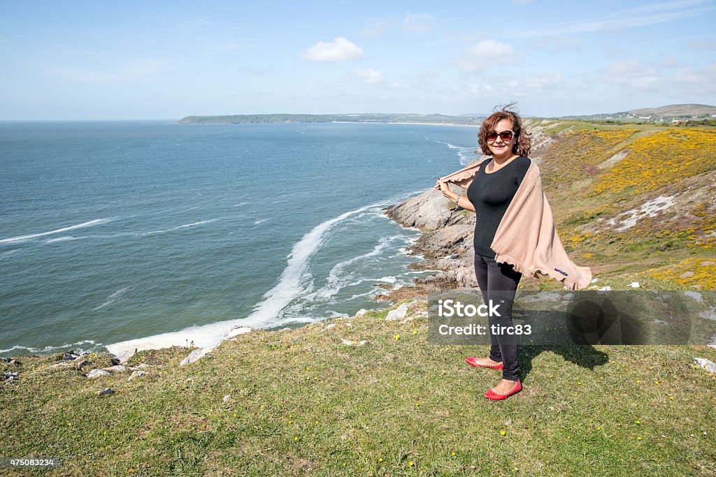 Mature hispanic woman standing on remote coastal headland 2015 Stock Photo