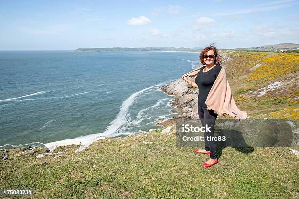 Mature Hispanic Woman Standing On Remote Coastal Headland Stock Photo - Download Image Now