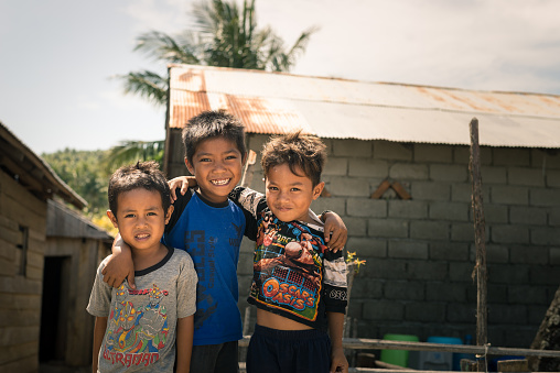 Boneoge,  Indonesia - August 31, 2014: Portrait of three smiling boys with poor clothings in the shanty village of Boneoge, Central Sulawesi, Indonesia. Concept of poverty and childhood in develping countries.