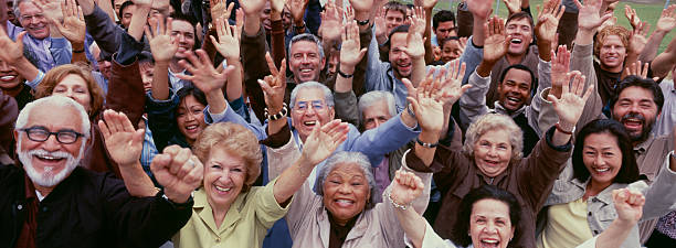 large group of multi-ethnic people cheering with arms raised - 65 69 jaar fotos stockfoto's en -beelden