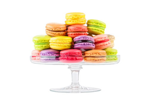 traditional french colorful macarons in a glass cake stand on white background