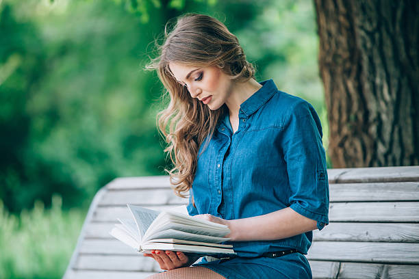 istock Girl reading a book in park 475092524