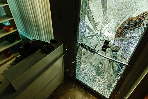 A robber using a sledgehammer to break the glass of a retail store.