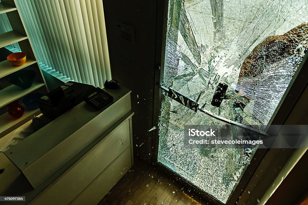 Robber using a sledgehammer, A robber using a sledgehammer to break the glass of a retail store. Burglary Stock Photo