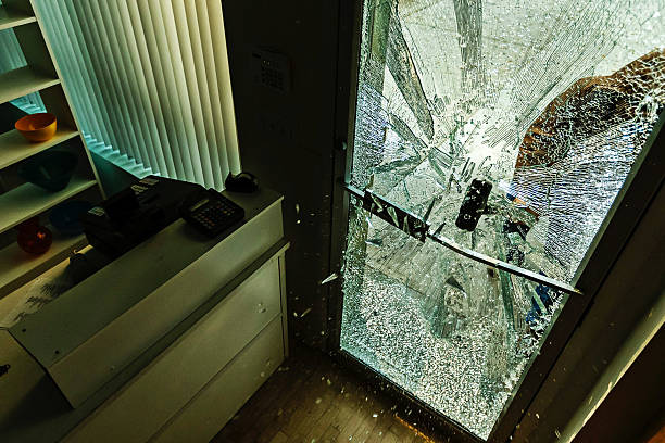 Robber using a sledgehammer, A robber using a sledgehammer to break the glass of a retail store. burglary photos stock pictures, royalty-free photos & images
