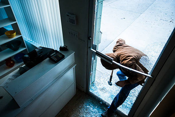 Robber using a sledgehammer, A robber using a sledgehammer to break the glass of a retail store. burglary crowbar stock pictures, royalty-free photos & images