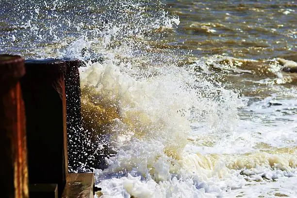 Waves crashing against a breaker on a stony beach.