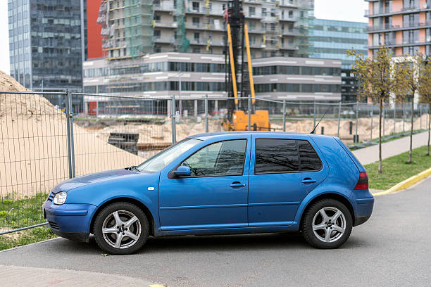 blue volkswagen golf iv estacionado próximo a construção site - playing golf - fotografias e filmes do acervo