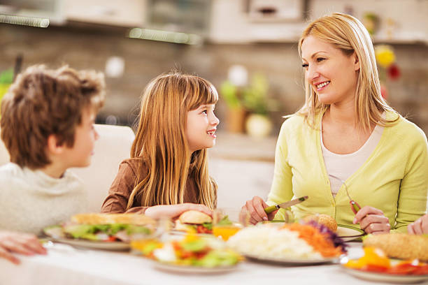 istock Smiling mother and children communicating during lunch. 475100296