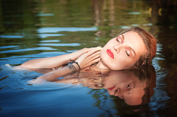 istock Beautiful young woman lying in the water 475100522