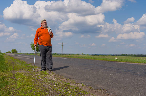 Hombre mayor caminando en la carretera de campo - foto de stock