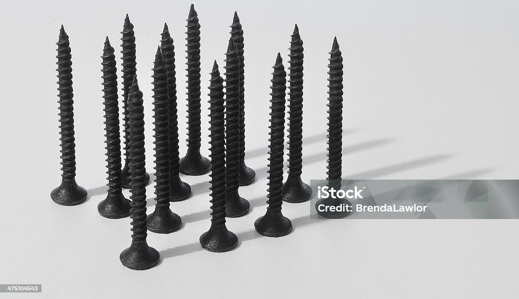 Black Steel Black steel drywall screws, arranged linearly and photographed on a matte white background. Close-up Stock Photo