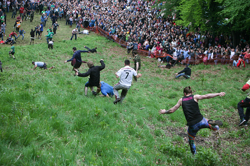 Brockworth, England - May 25, 2015: Entrants chasing the cheese at the 2015 ‘Cheese Rolling’ held at Cooper’s Hill, in the Cotswolds.
