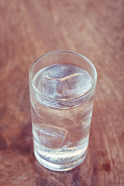istock Drinking water with ice in glass on wooden table 475110084