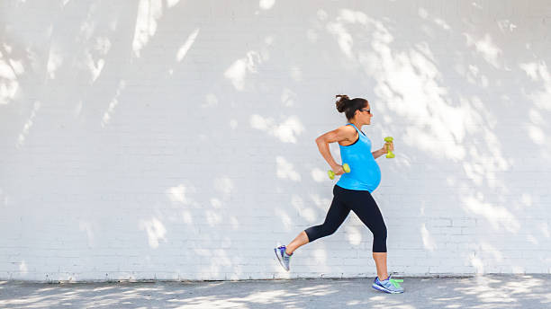 giovane donna incinta fare jogging lungo strada in città. - human pregnancy exercising relaxation exercise sport foto e immagini stock