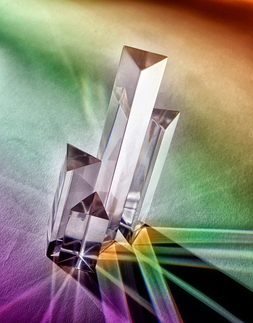 Crystal prisms photographed on tabletop with rainbow shadows.