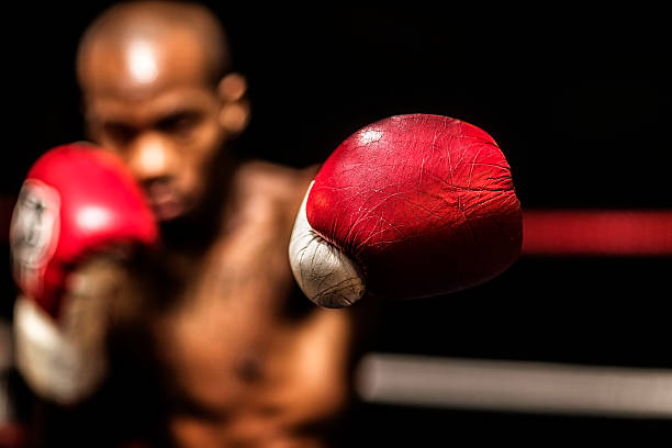 Young woman boxer. Young woman boxer holding up red boxing gloves ready to box in a boxing ring. knockout stock pictures, royalty-free photos & images