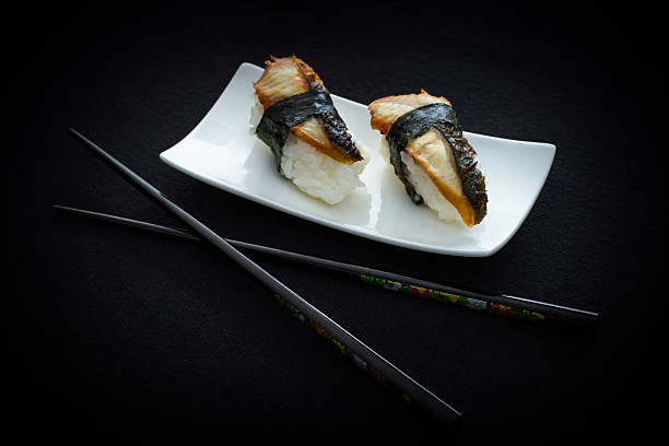 istock Two nigiri eel sushi and chopstick on black 475113476