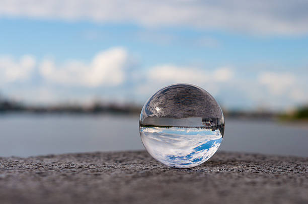 istock Glass transparent ball on river background and grainy surface. Water 475114604