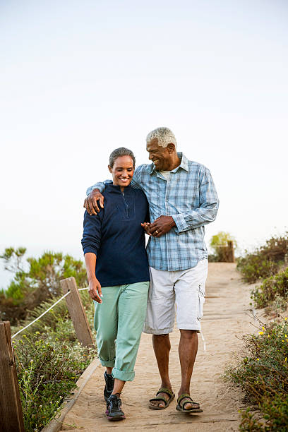 casal caminhando na boardwalk. - retirement couple beach senior adult - fotografias e filmes do acervo
