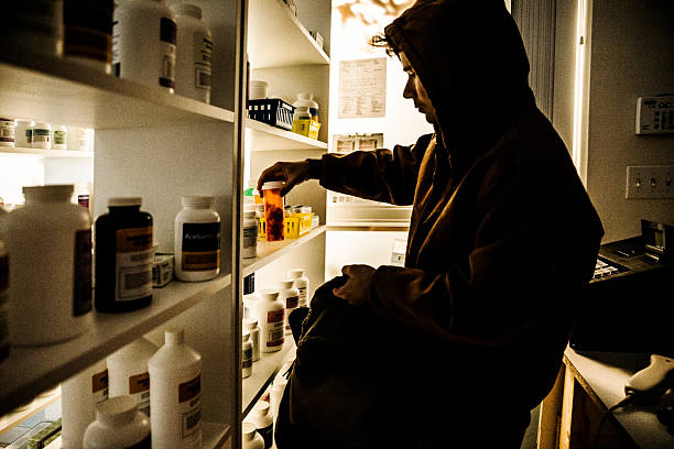 Drug addict stealing prescriptions. A young male drug addict stealing prescriptions off the shelf of a pharmacy. self harm photos stock pictures, royalty-free photos & images