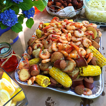 Boil new potatoes being poured on corn on the cop and sausages. Low Country Boil.