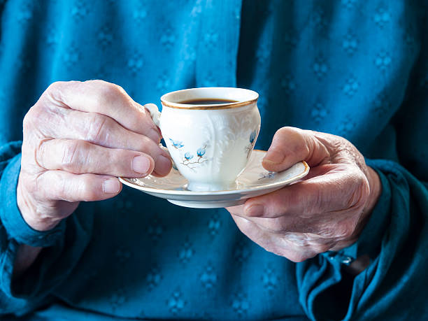 Elderly hands holding a cup of coffee stock photo