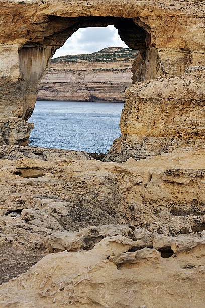 Rocky beach, consisting largely of sandstone formations, at the small fishing village of Agia Ermioni at the eastern coastline of the Greek Island of Chios in the Aegean Sea on a sunny morning in autumn (October). The image was captured on old-fashioned 35mm daylight ISO 200 film by an analogue (or analog) 35 mm film camera. The granularity in the image is real film grain (due to the presence of small particles of dyed silver halide on the negative). Minimal post processing has been done (only adjustment of histogram). The image is part of a series of rocky beaches on the Greek Island of Chios.