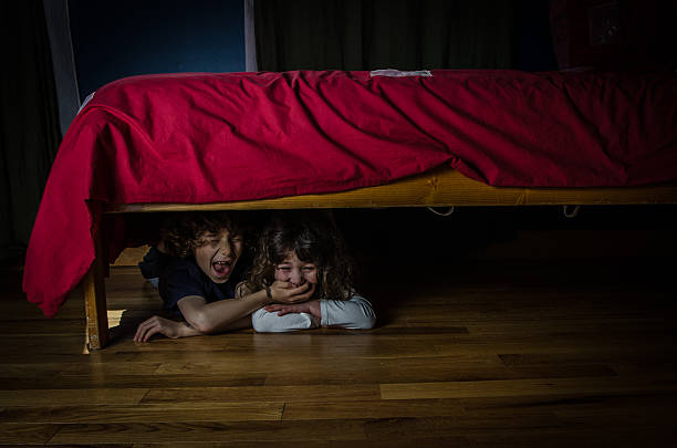 istock Kids hidden under the bed with fear and crying 475138900
