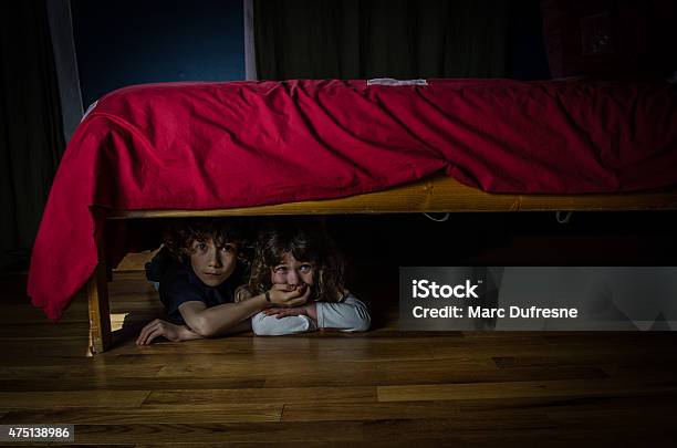 Kids Hidden Under The Bed With Fear And Crying Stock Photo - Download Image Now - Hiding, Below, Bed - Furniture